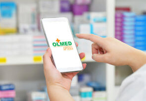 zdjęcie telefonu z grafiką na ekranie z Olmed apteki on-line trzymanego przez farmaceutę